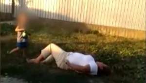 Imagini revoltătoare! Femeie beată mangă, căzută pe marginea drumului: fiul ei, de numai 6 ani, îi ținea sticla de bere (VIDEO)